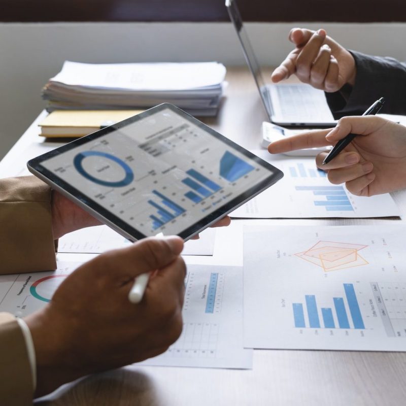 Business team brainstorming data target financial on digital tablet and paperwork.